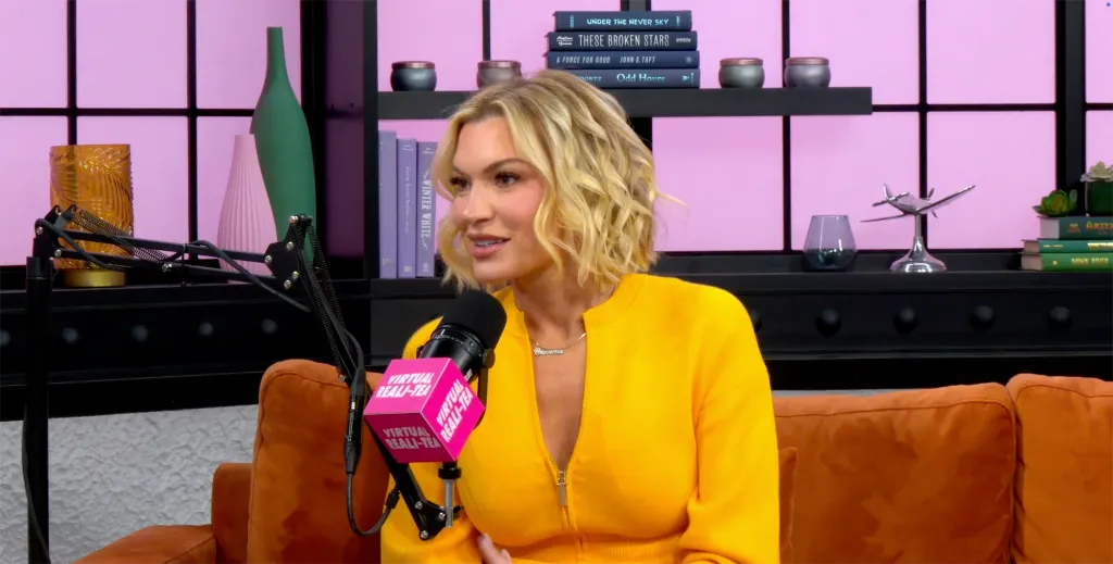 Lindsay Hubbard speaking into a "Virtual Reali-Tea" podcast microphone while seated on an orange couch.