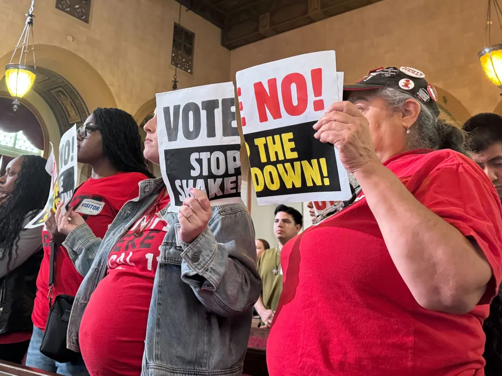 Protesters holding "VOTE NO!" and "STOP THE SHAKEDOWN!" signs at Los Angeles City Hall.