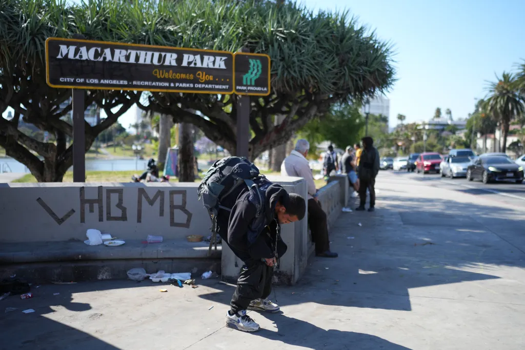 A man holding a pipe is hunched over in MacArthur Park, where arrests were made for drug-related charges.