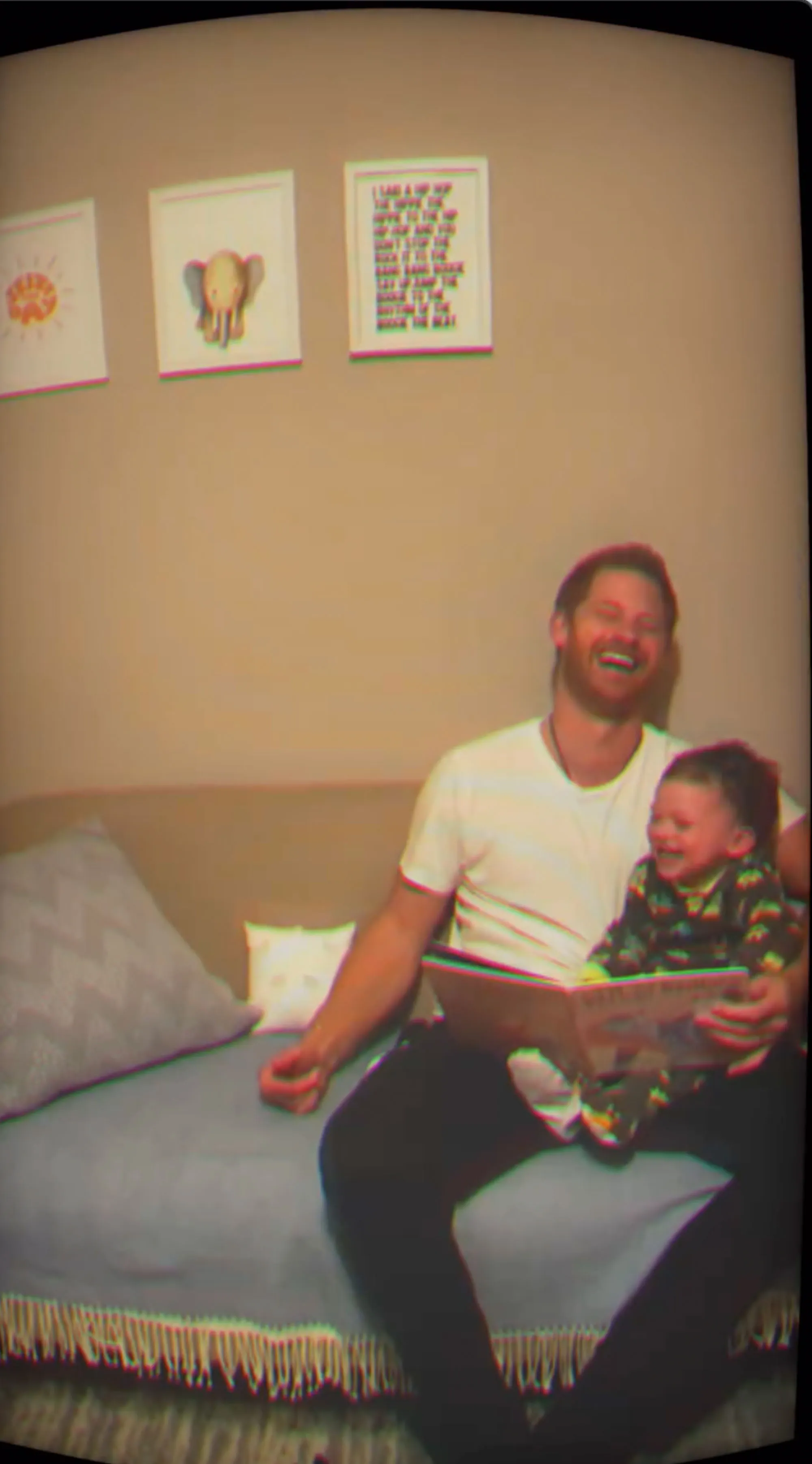 Prince Harry laughing while reading a book to his son Archie.