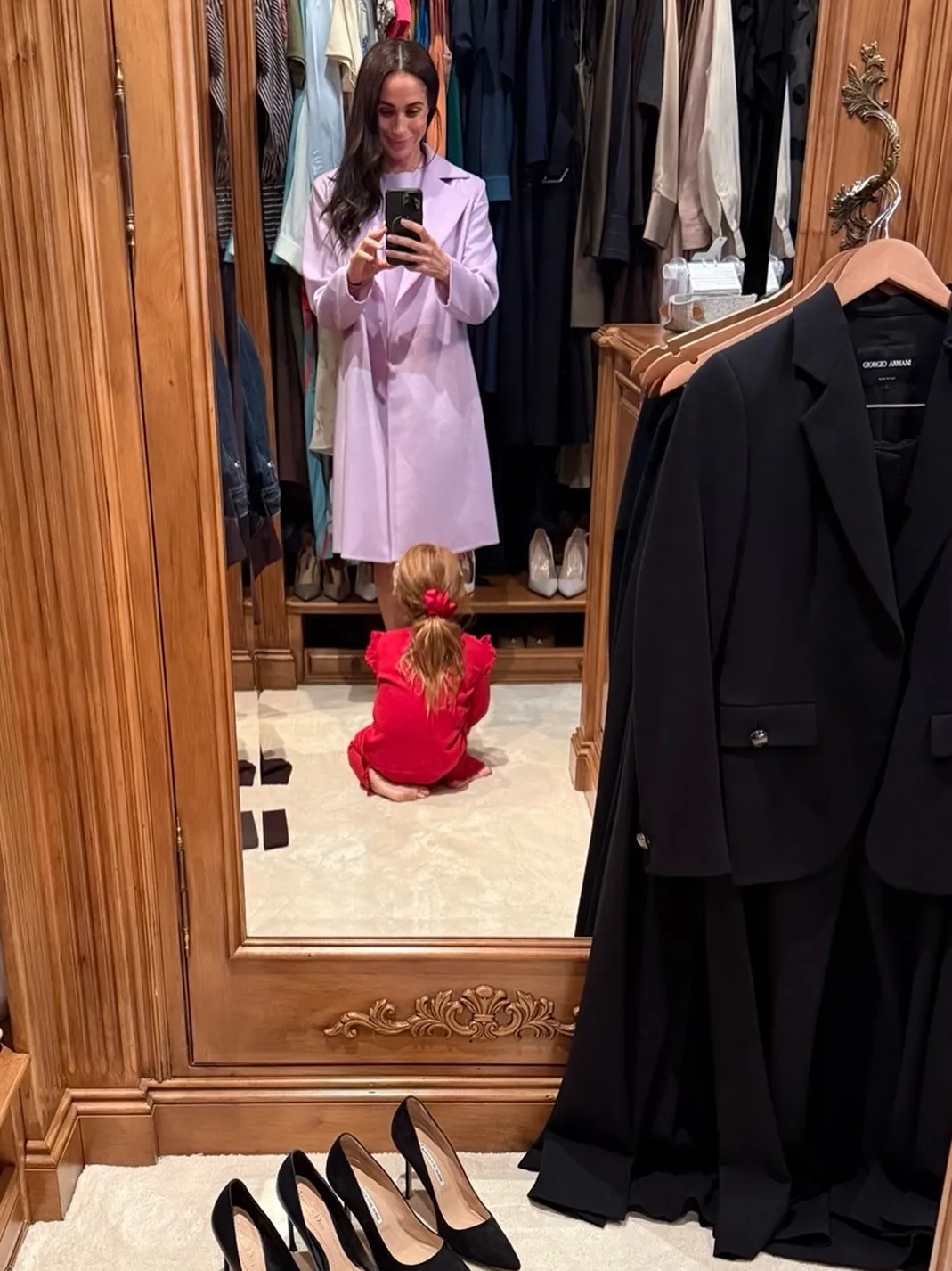 Meghan Markle takes a mirror selfie with her daughter, Lilibet, who is on the floor looking at her shoes.