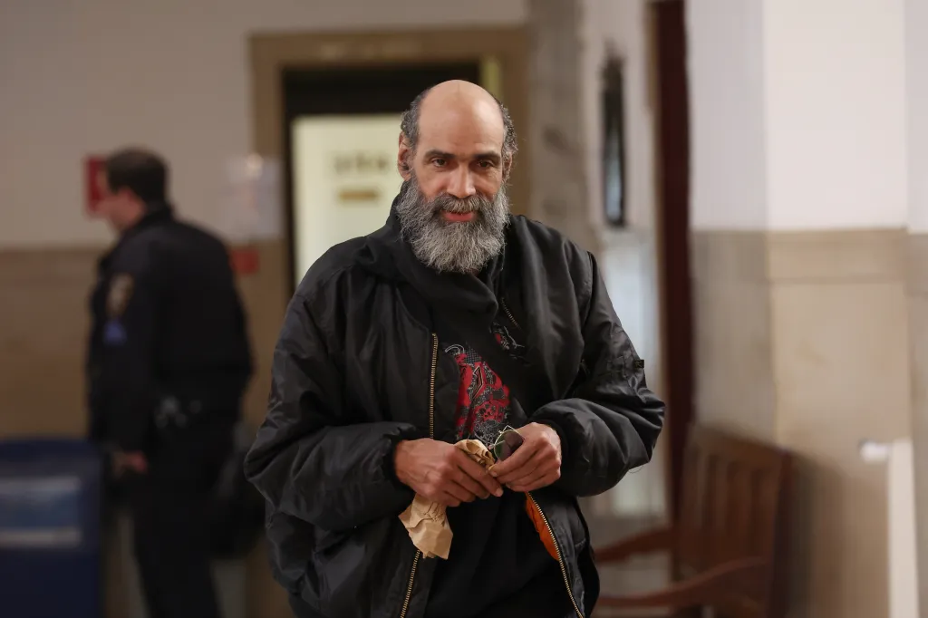 Melvin Dejesus, with a gray beard and black jacket, smiles while arriving at Civil Court.
