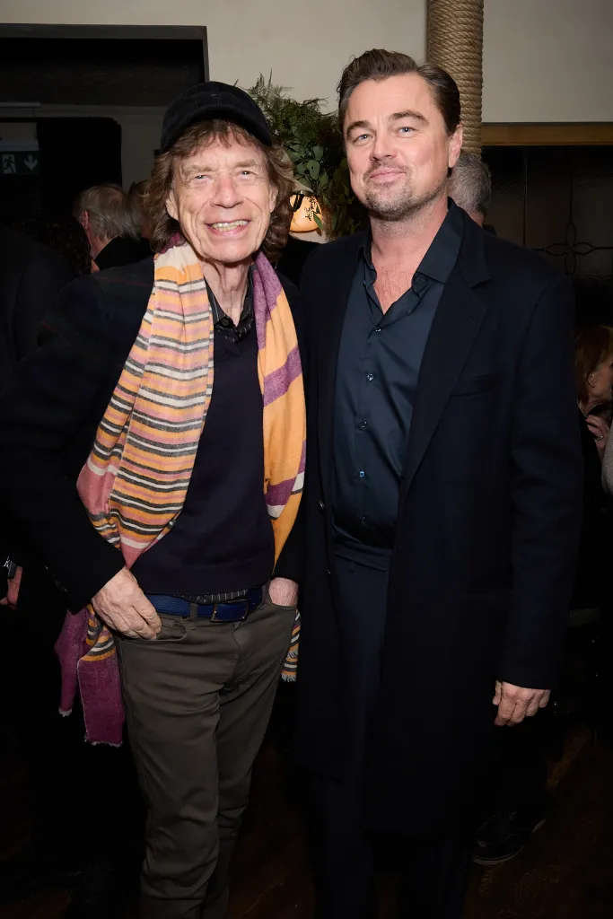 Mick Jagger and Leonardo DiCaprio smiling at the "One Battle After Another" celebration.