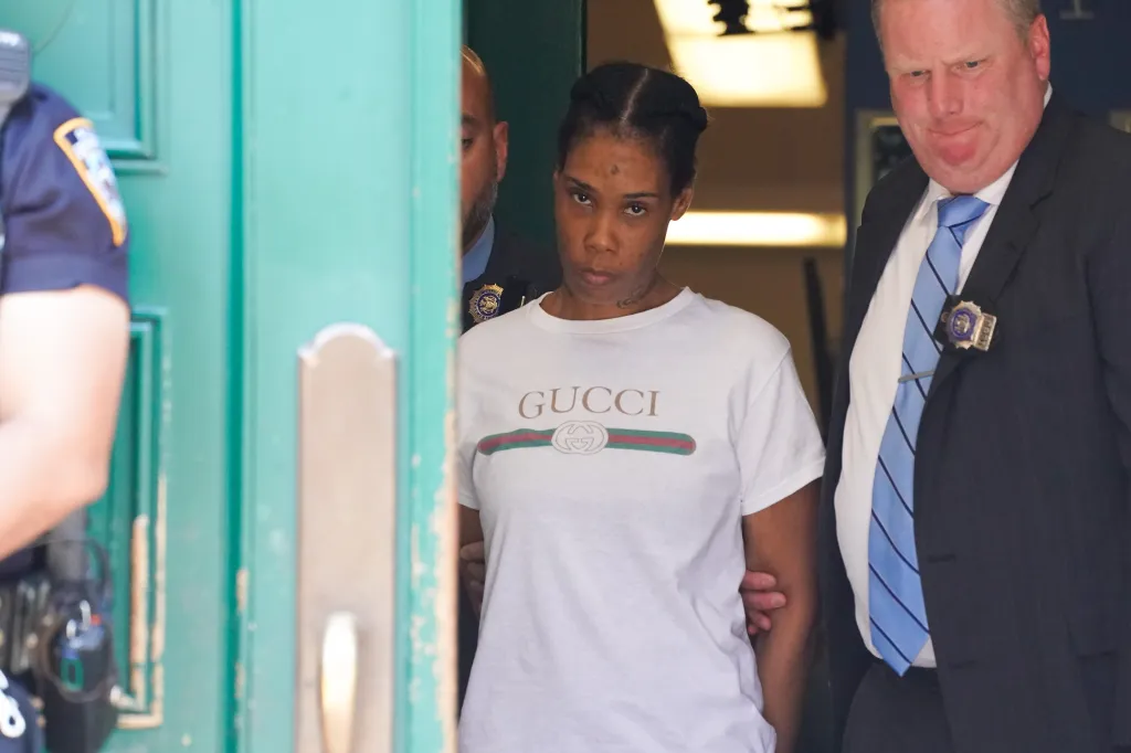 Navasia Jones, wearing a white "Gucci" t-shirt, is escorted by officers.