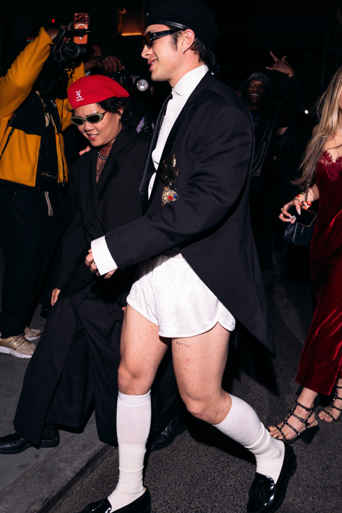 Hudson Williams in a black tuxedo blazer, white shorts, and knee-high socks arriving at the GQ after-party in London.
