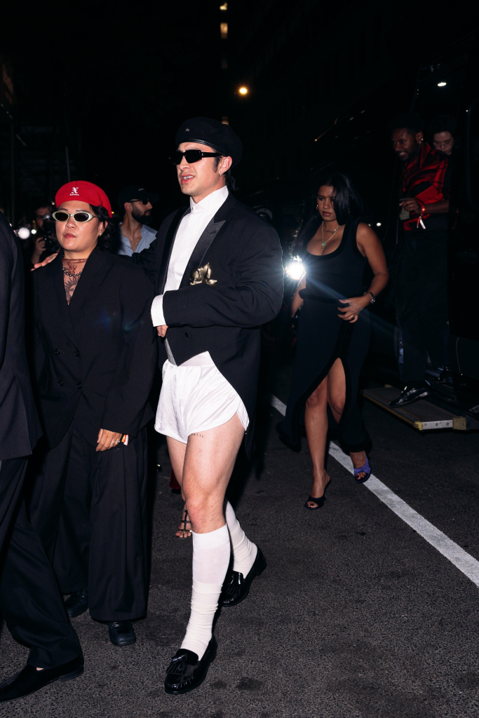Hudson Williams wearing a tuxedo blazer, white shorts, knee-high socks, and dress shoes, arriving at the GQ after-party in London.