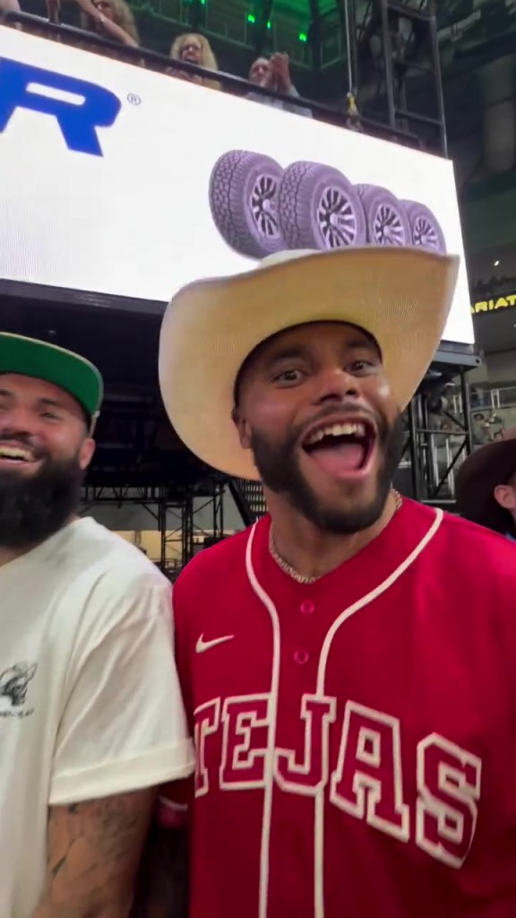 NFL star Dak Prescott wearing a cowboy hat and a red baseball jersey with "TEJAS" written on it.