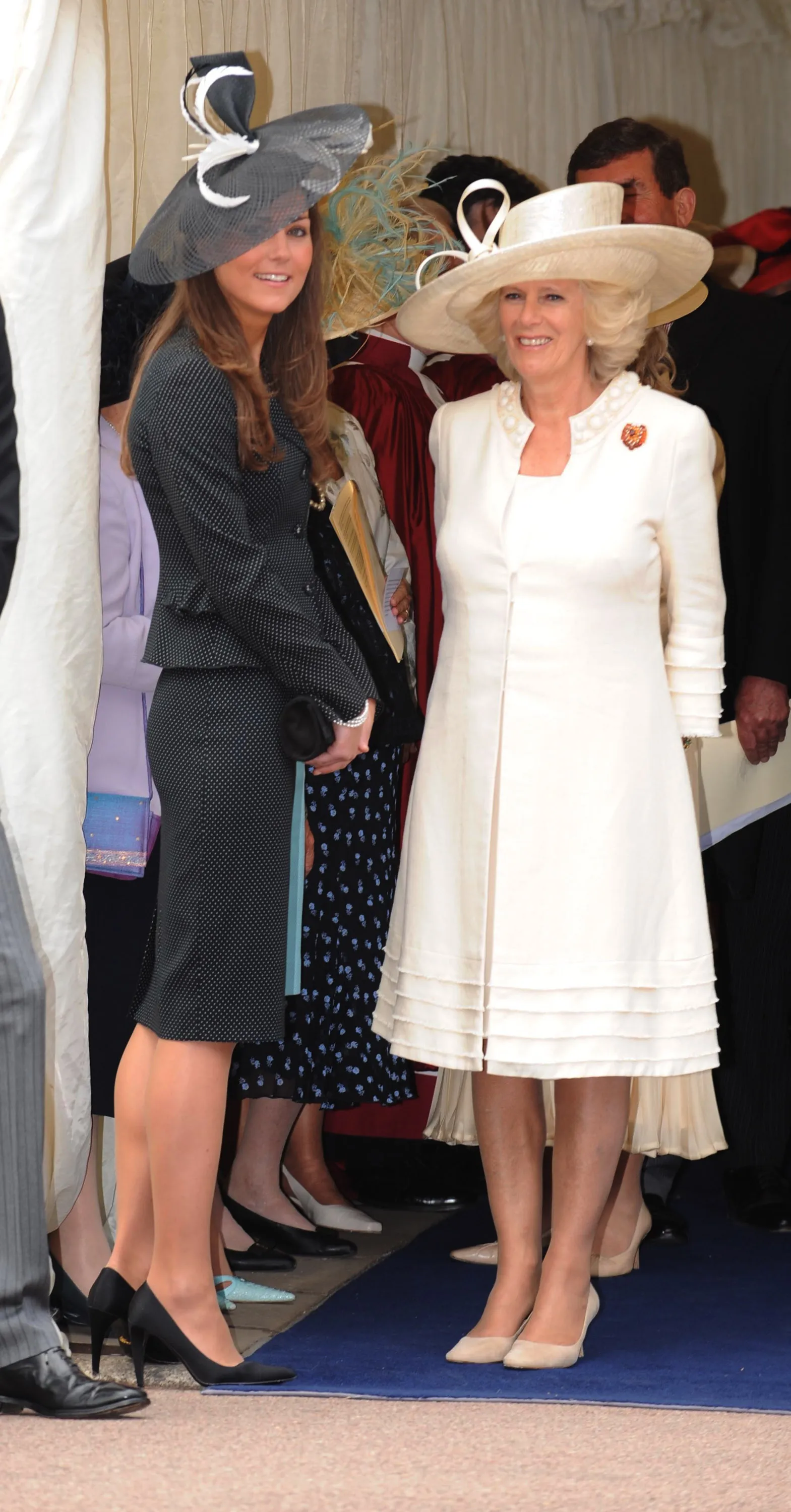 Kate Middleton in a black suit and Camilla, Duchess of Cornwall in a white outfit, both wearing hats, attending the Order of the Garter service.