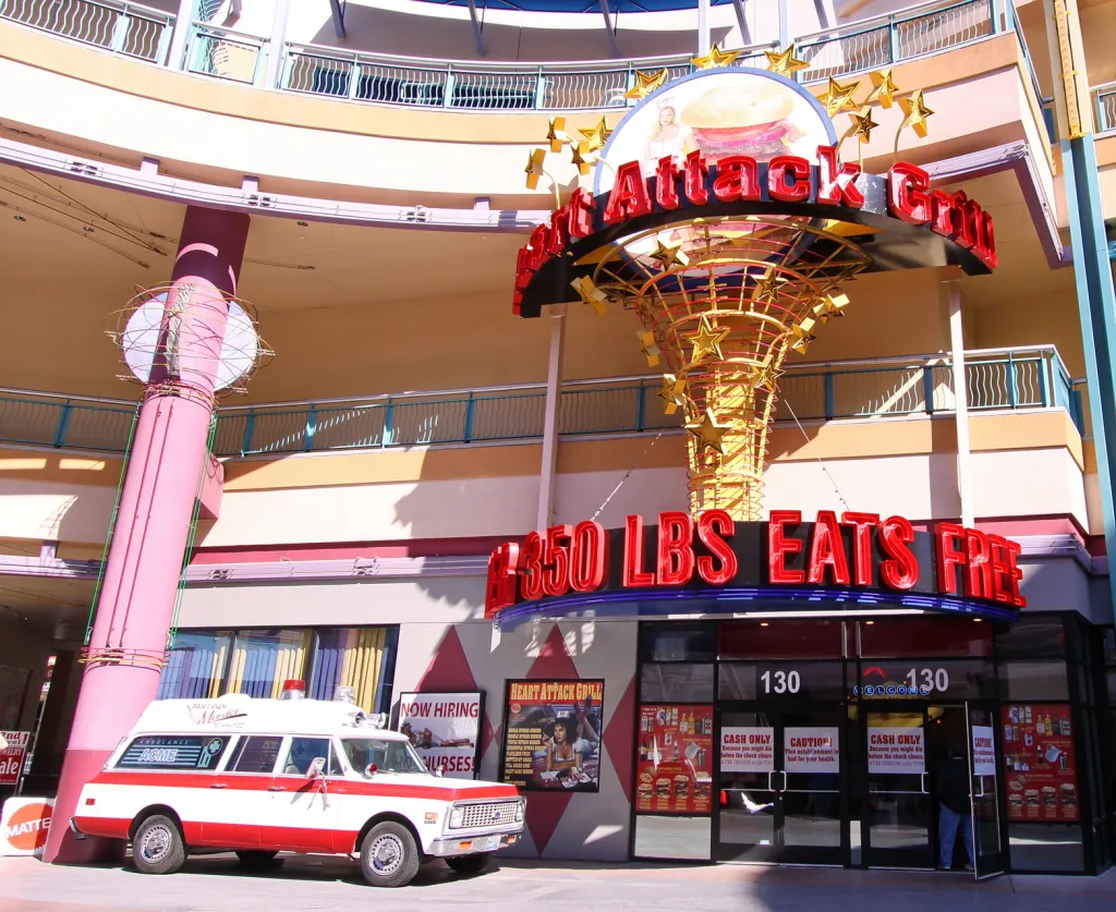 The Heart Attack Grill restaurant with an ambulance parked outside and a sign that reads "350 LBS EATS FREE."