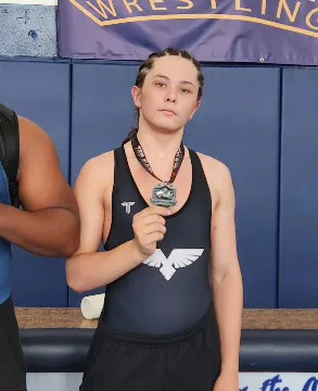 Cain Clark in a wrestling singlet, holding a medal.