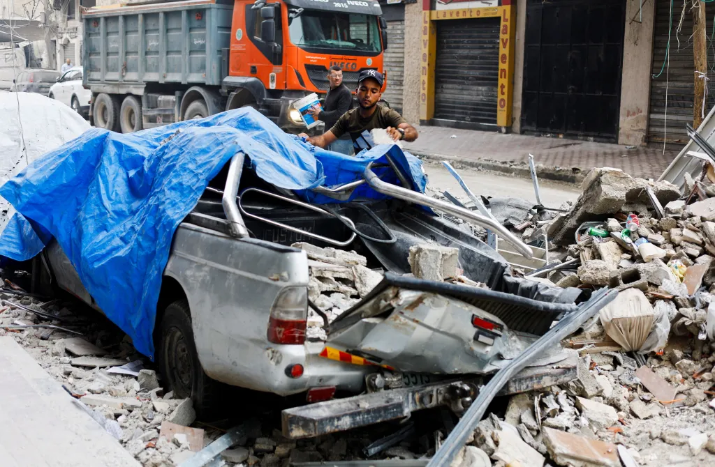 A Palestinian man moves debris next to a destroyed vehicle as he inspects the site of an Israeli airstrike on a residential building on Tuesday, in Gaza City, May 27, 2026.