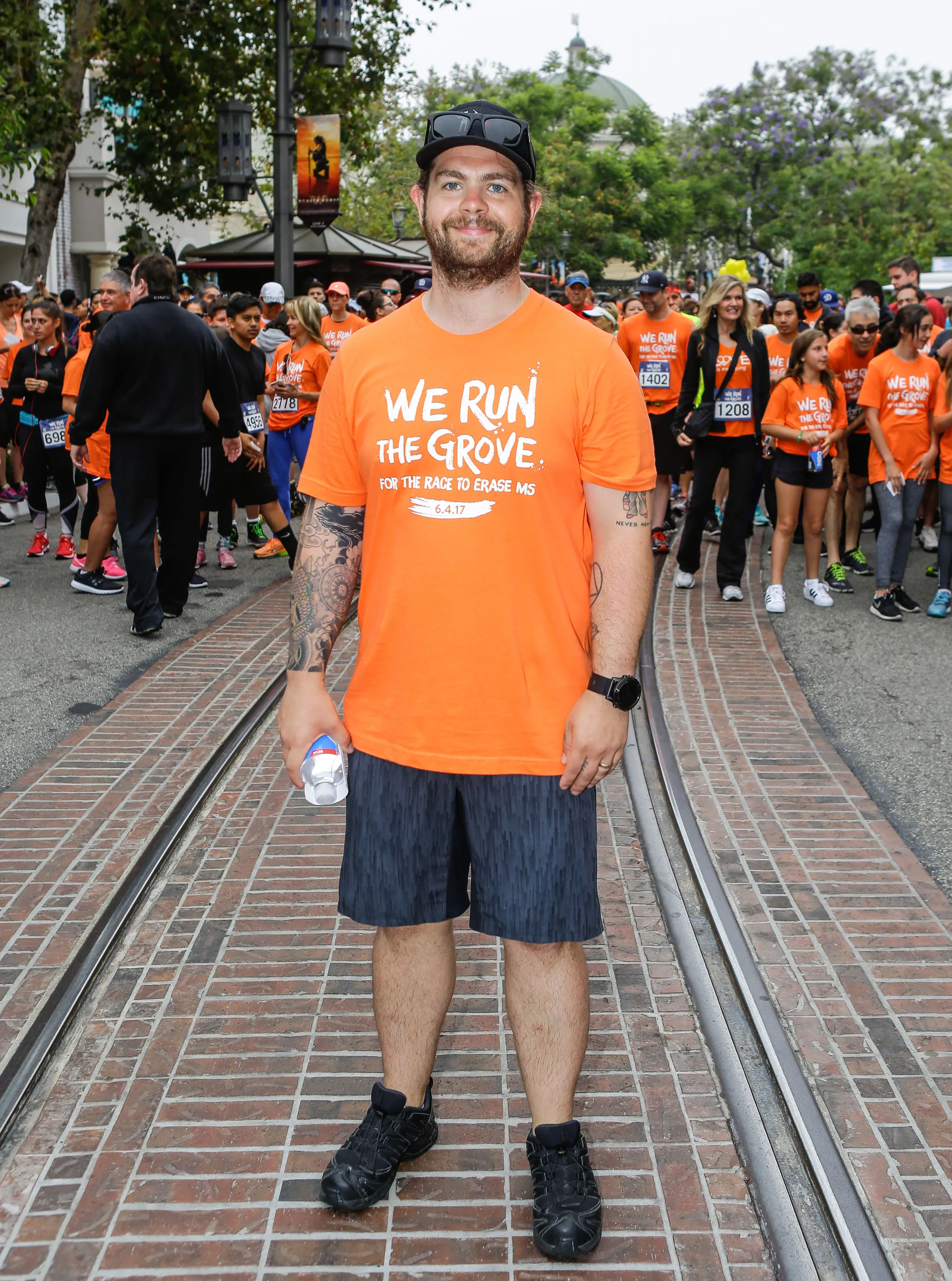 Jack Osbourne stands in an orange t-shirt for "We Run The Grove For The Race To Erase MS"