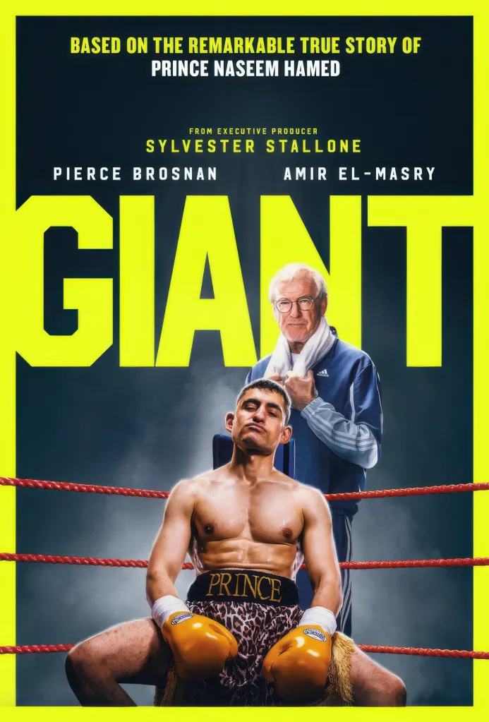 Movie poster for "Giant" featuring Amir El-Masry as Prince Naseem Hamed in leopard print shorts and golden boxing gloves, with Pierce Brosnan behind him as his trainer, against a bright yellow and dark grey background.