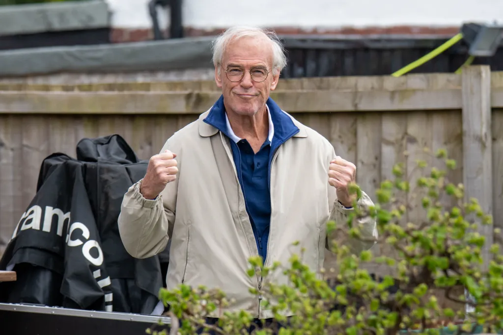 Pierce Brosnan as Brendan Ingle with a balding grey hairstyle and tracksuit on set of "Giant".
