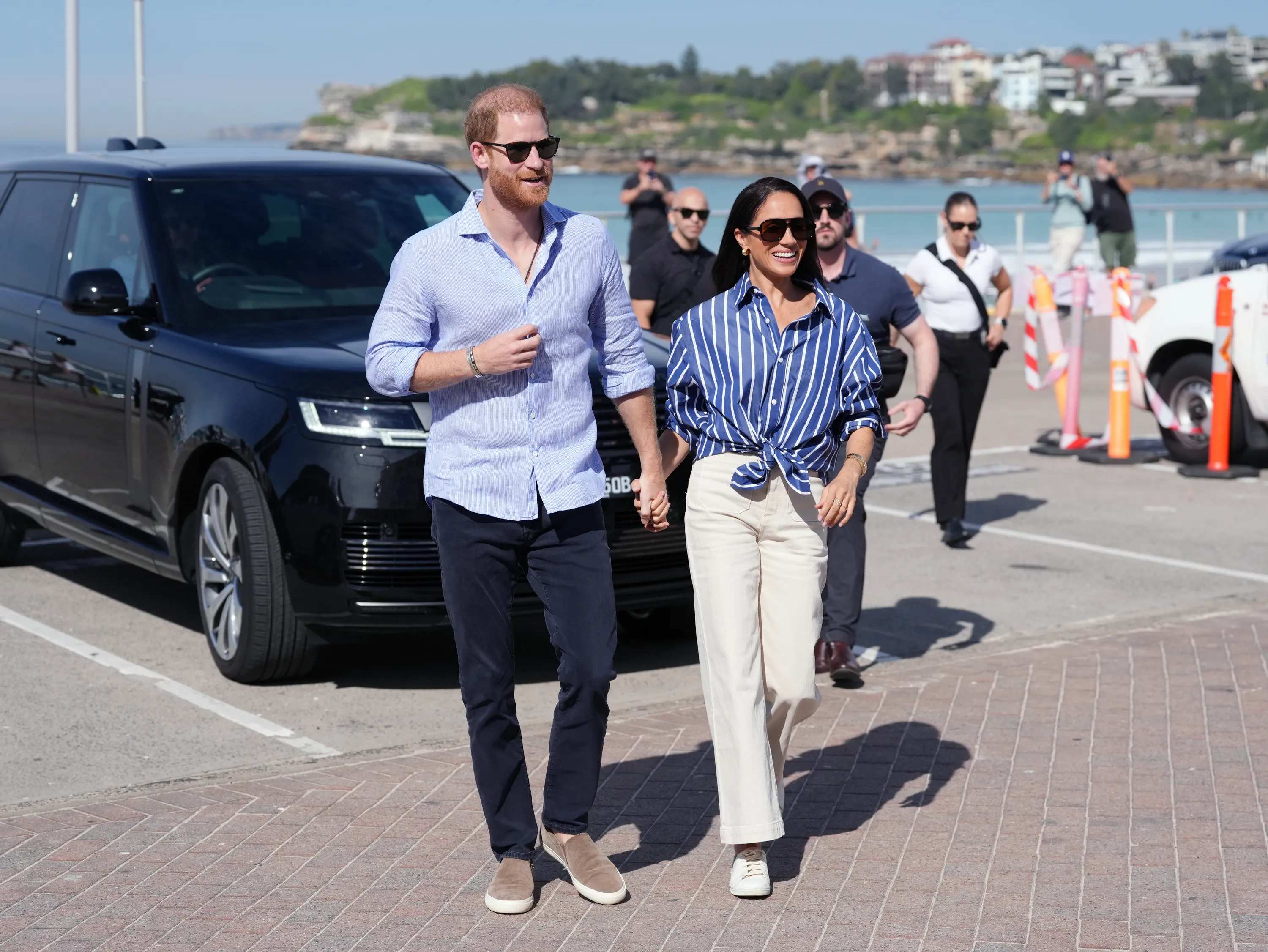 Prince Harry and Meghan Markle walk hand-in-hand toward Bondi Surf Bathers' Life Saving Club.