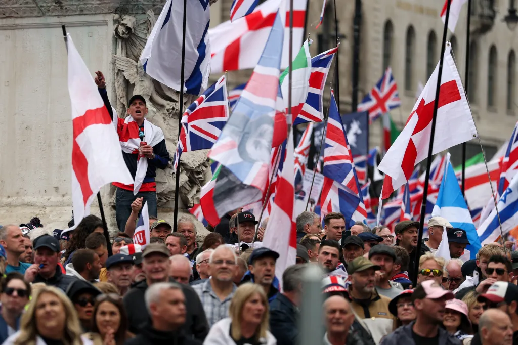 A crowd of people waving British and English flags at a "Unite the Kingdom" rally in London.