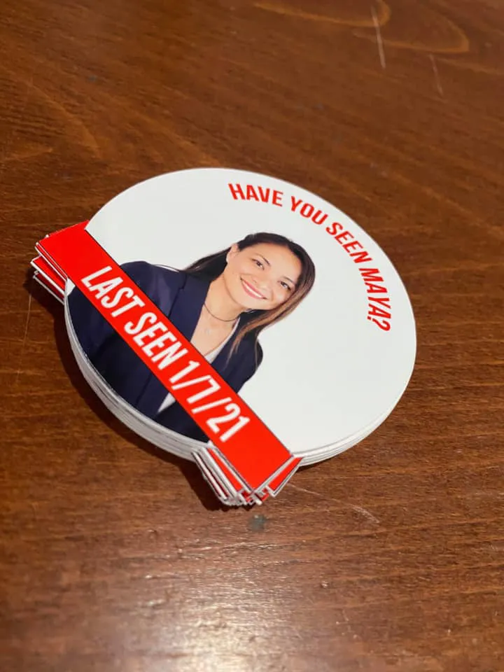 A stack of white circular stickers with a photo of Maya Millete, with the text "HAVE YOU SEEN MAYA?" and "LAST SEEN 1/7/21".
