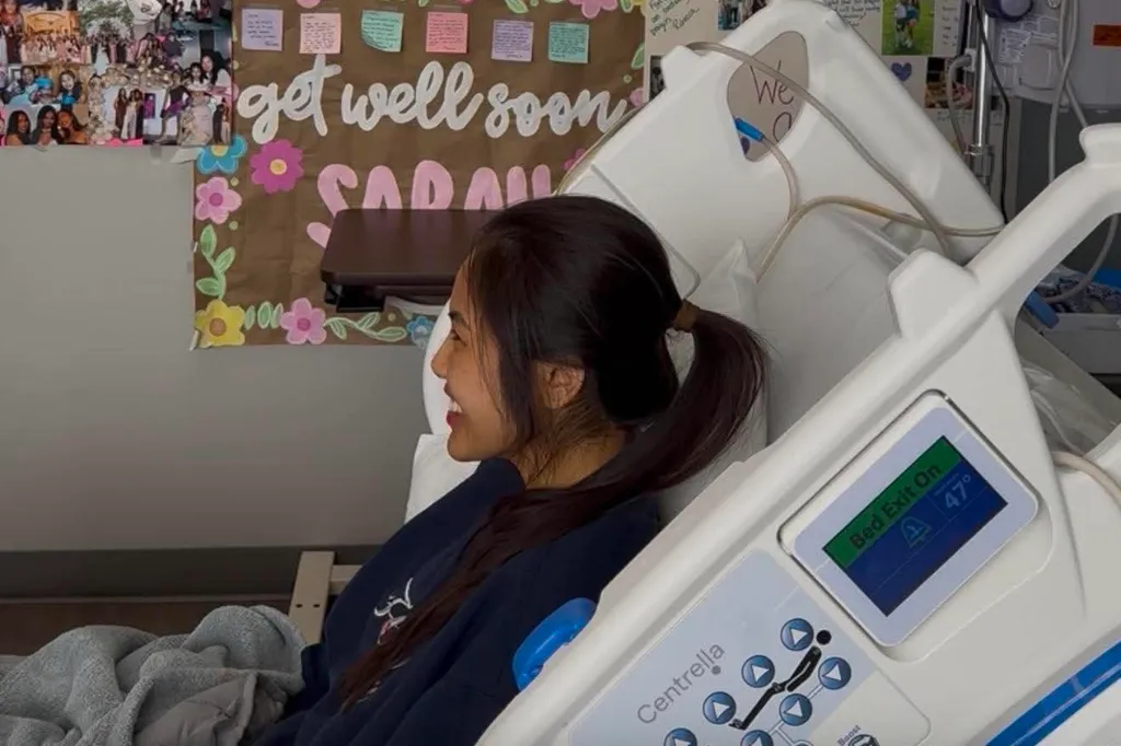 Sarah Danh in a hospital bed with a "get well soon" sign behind her.