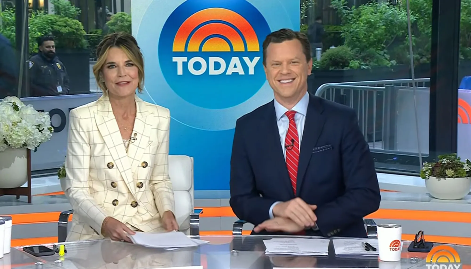 Savannah Guthrie and another Today show host smiling behind a news desk.