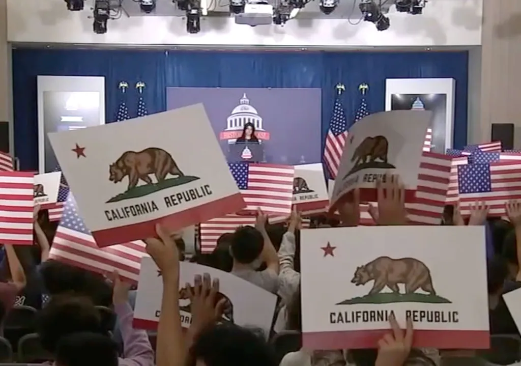 Students holding California Republic and American flags at a school assembly.