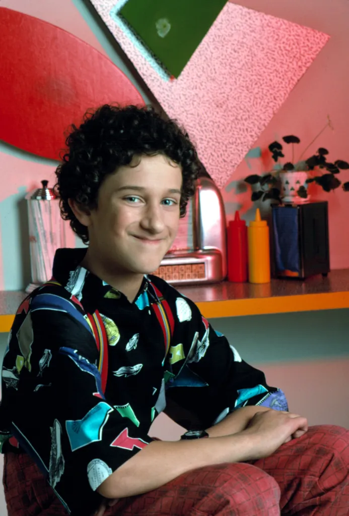 Dustin Diamond as Screech, from Saved by the Bell, sits in a diner.