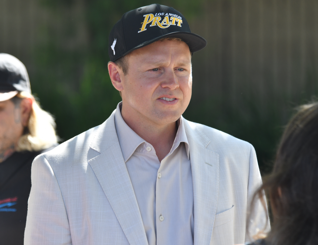 Spencer Pratt wearing a black and yellow "Los Angeles Pratt" hat and a light suit while meeting with voters in Tim Gilliam Park.