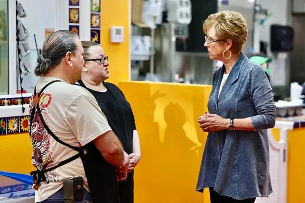 Stacy Korsgaden, candidate for California insurance commissioner, speaks to two people.