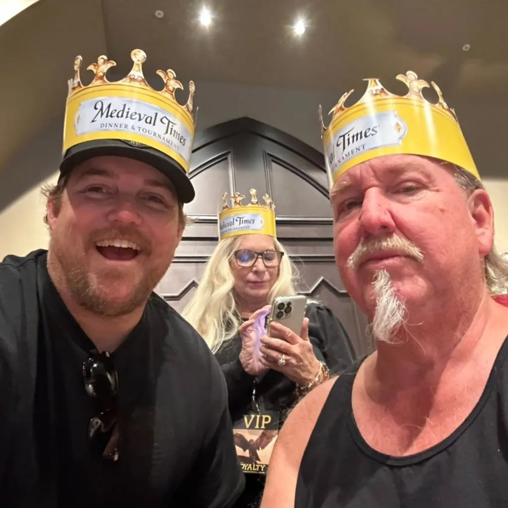 Brandon Sheets and Darrell Sheets wearing paper crowns with "Medieval Times Dinner & Tournament" printed on them, with a woman in the background.