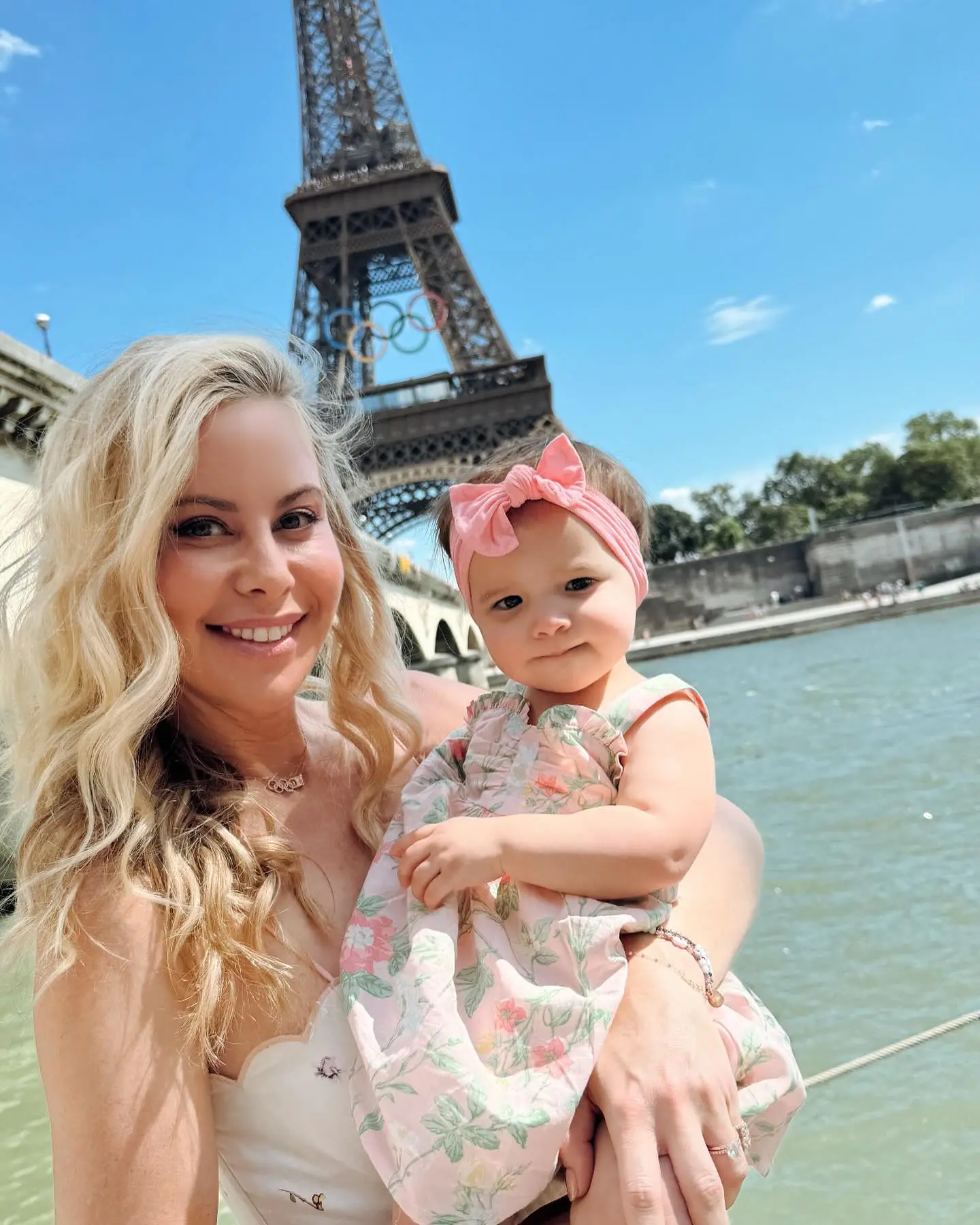 Tara Lipinski with her daughter Georgie in front of the Eiffel Tower, adorned with Olympic rings.