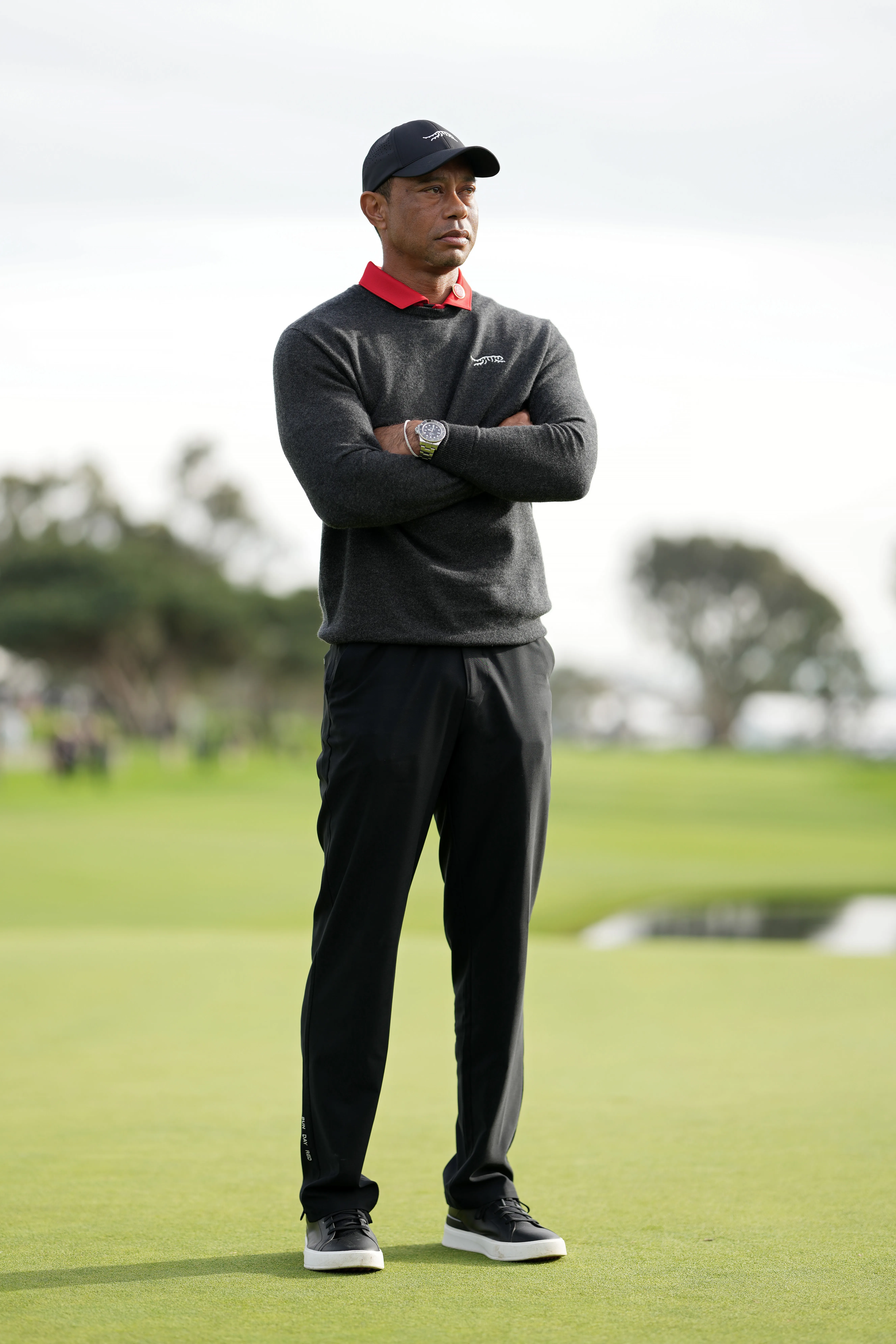 Tiger Woods stands on a golf course, looking intently at the trophy ceremony.