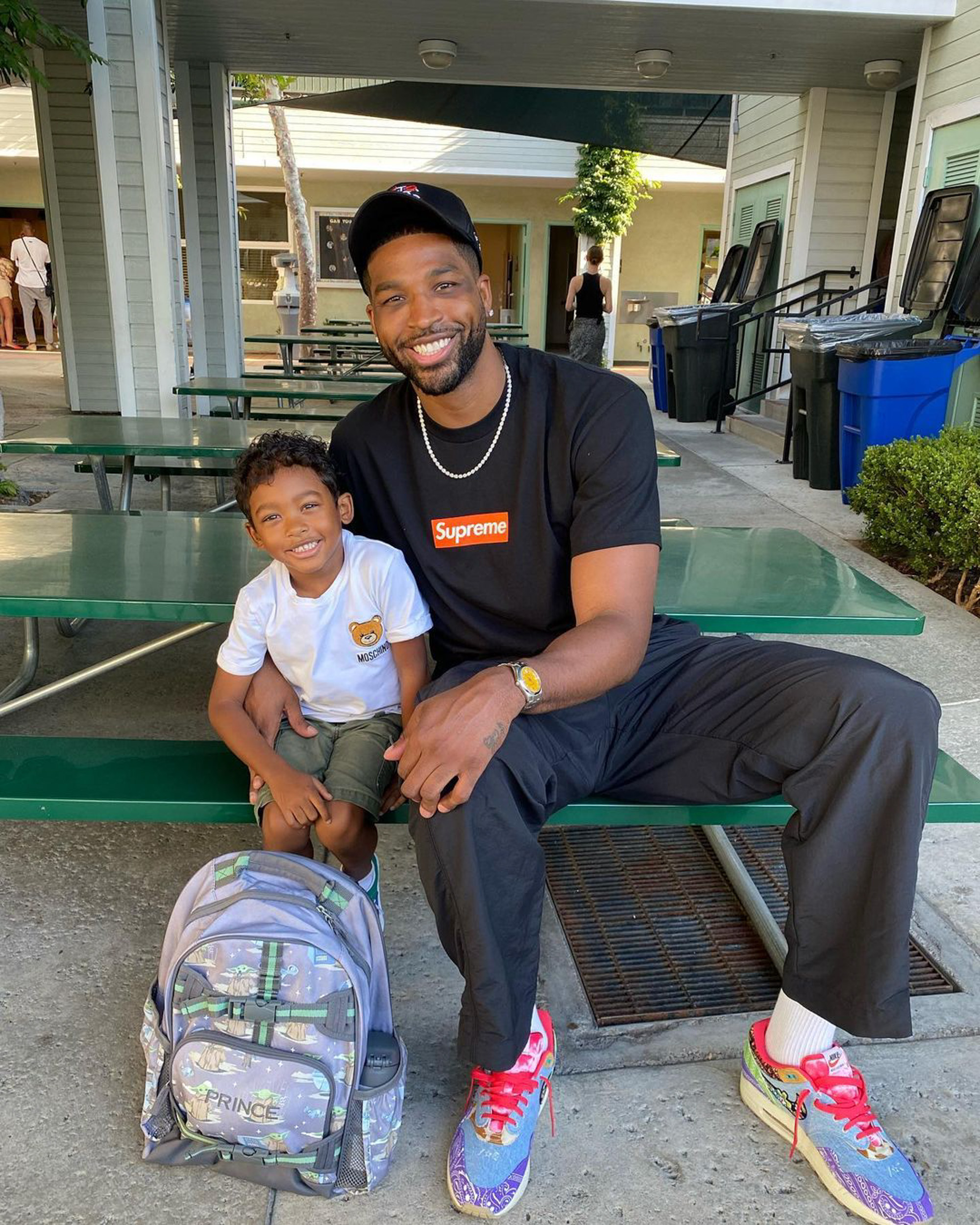 Tristan Thompson poses with his son on a green picnic bench.