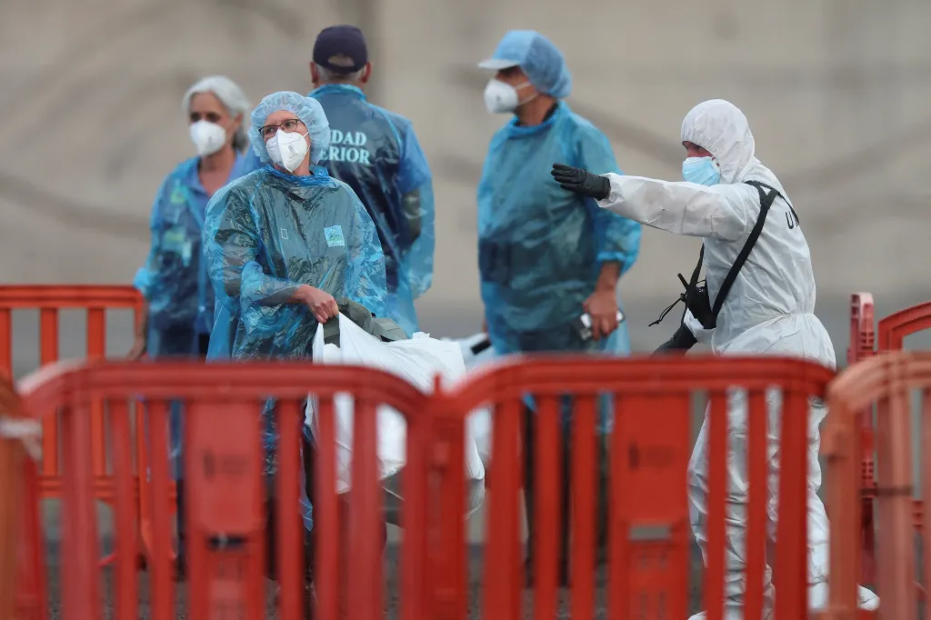 Personnel in protective gear instruct passengers disembarking a cruise ship after a hantavirus outbreak in Tenerife, Spain.