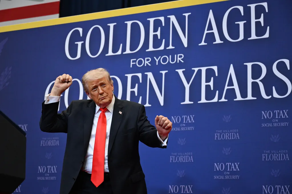 President Trump dances on stage in front of a blue backdrop that reads "GOLDEN AGE FOR YOUR GOLDEN YEARS" and "NO TAX ON SOCIAL SECURITY."