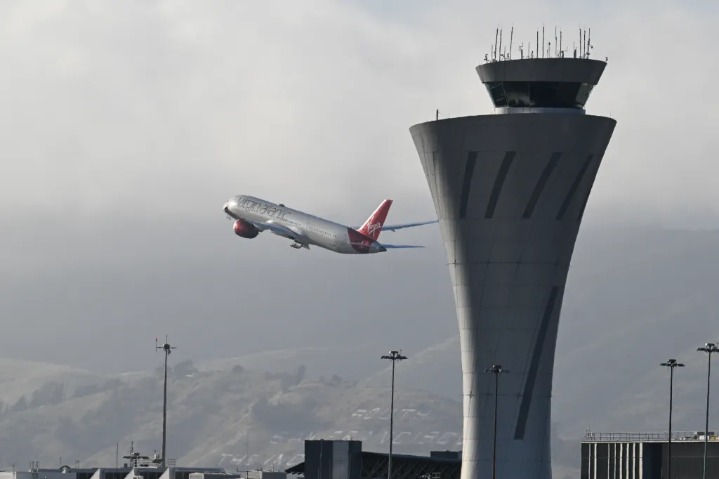 A Virgin Atlantic plane takes off next to the San Francisco International Airport (SFO) air traffic control tower.