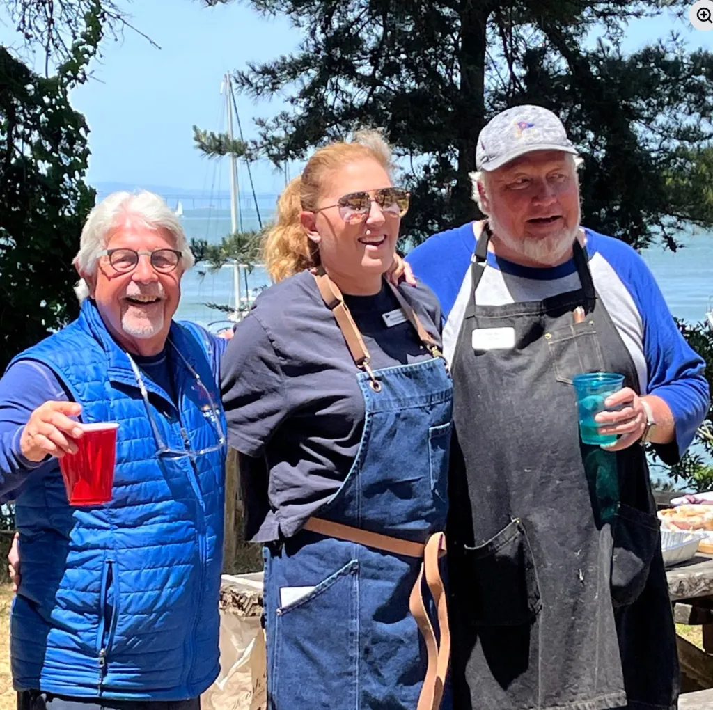 Marisa McArthur in the middle of two men at the Sausalito Yacht Club.