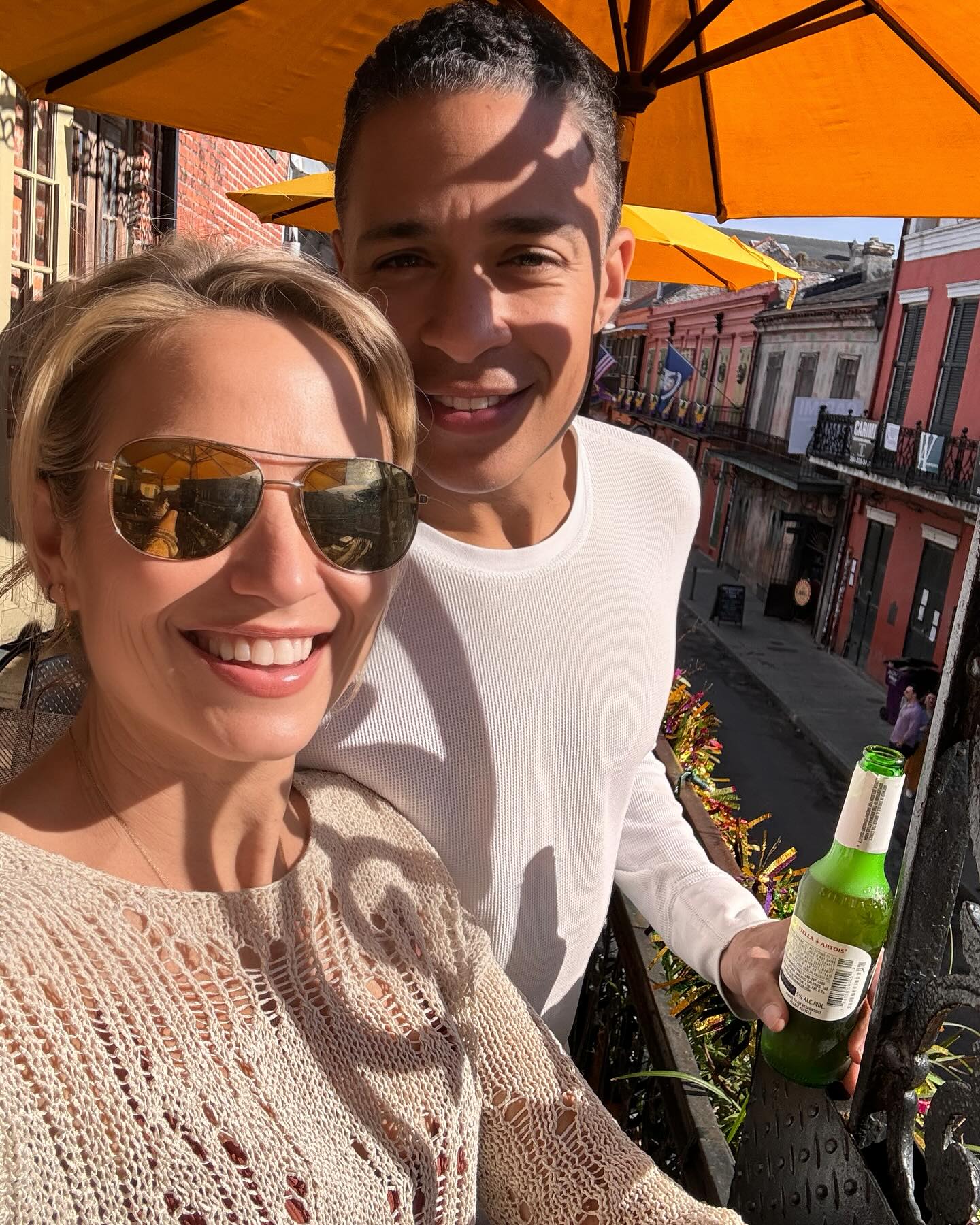 Amy Robach and TJ Holmes taking a selfie on a balcony.