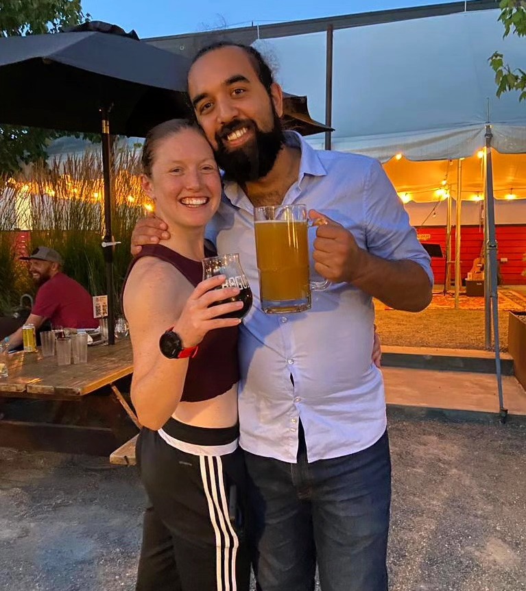 Catie and Josh smiling while holding drinks.