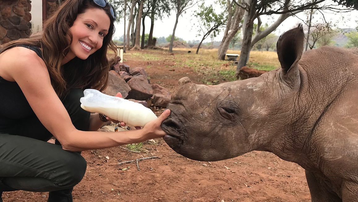 Shannon Elizabeth feeding a baby rhino a bottle of milk.