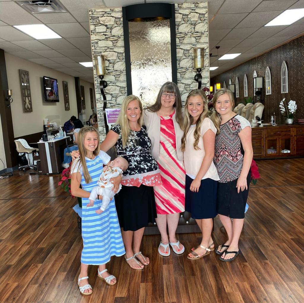A family of six, including a baby, posing inside a nail salon.