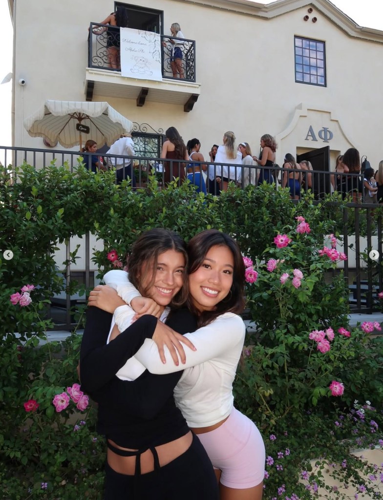 Two smiling women in front of the Alpha Phi sorority house.