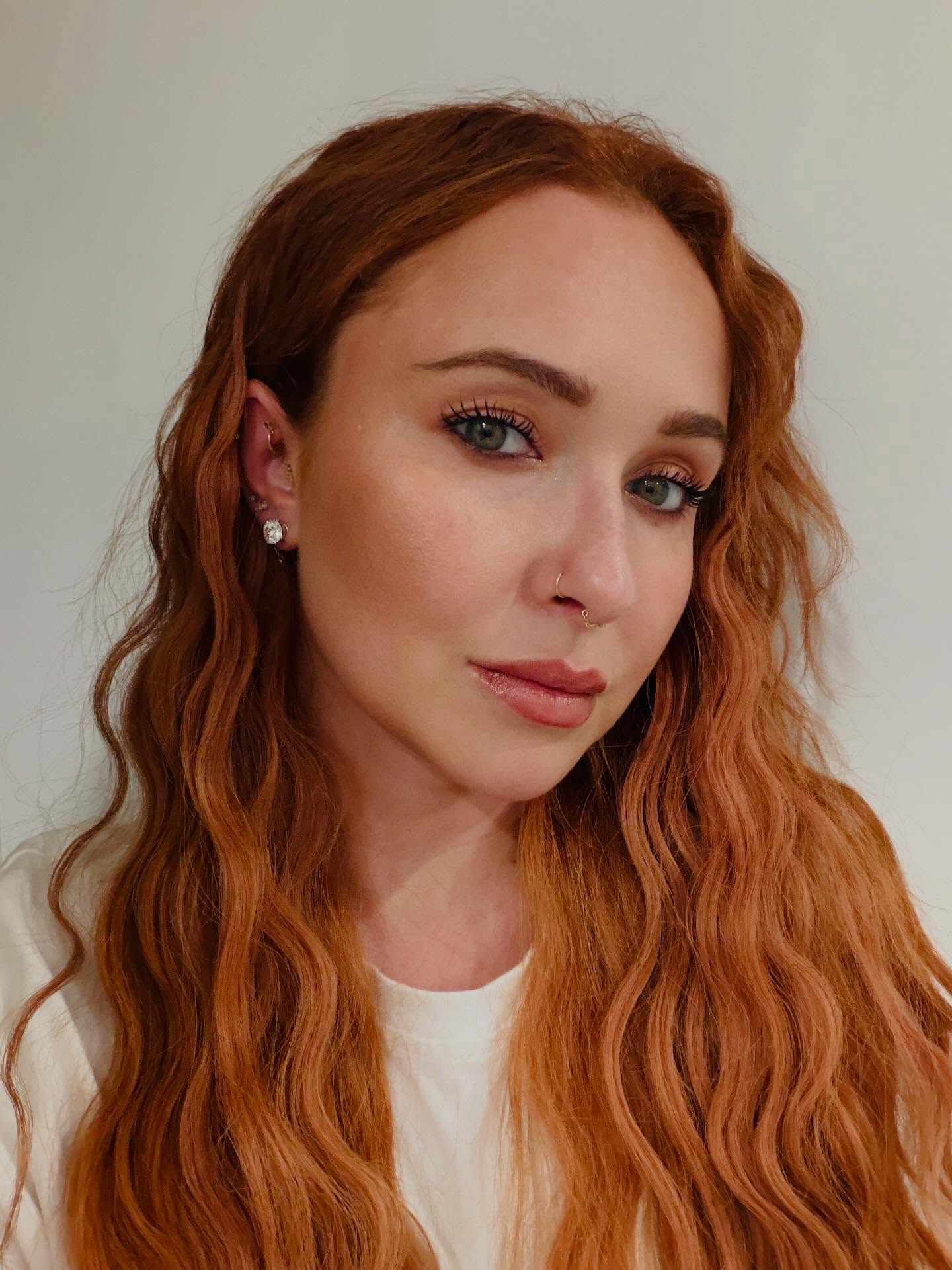 Headshot of Hayden Panettiere with long, wavy red hair, light green eyes, and a nose ring.
