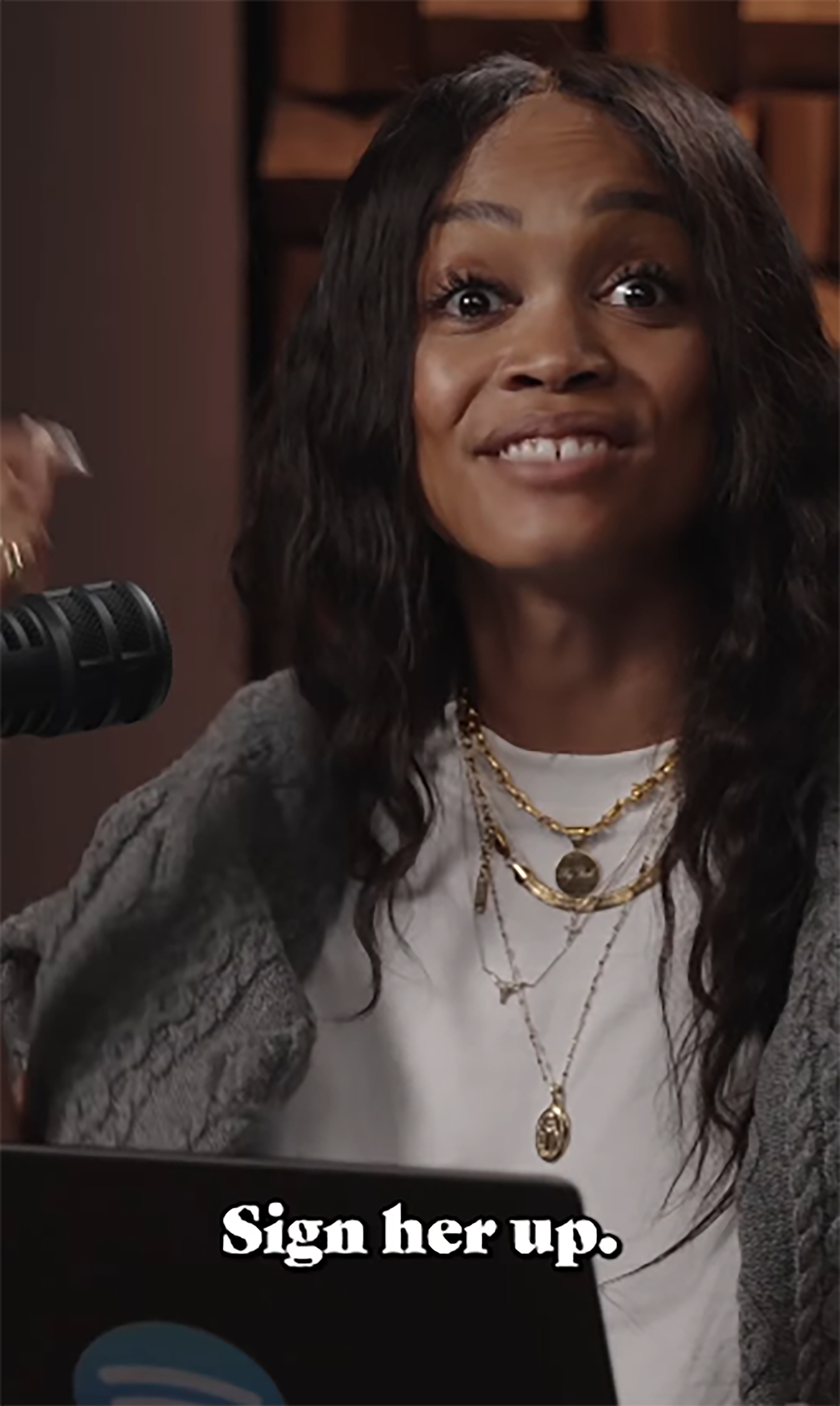 Rachel Lindsay on a podcast, smiling and looking up, with a microphone to her left.
