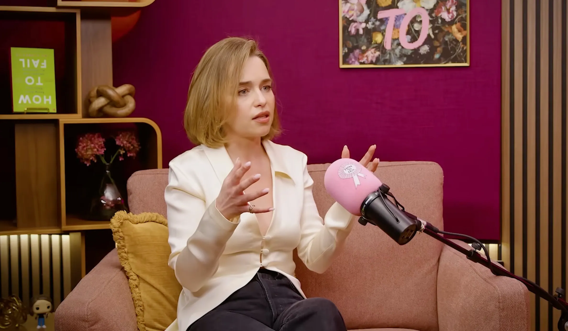 Emilia Clarke speaking into a pink microphone with "How To Fail" written on it.