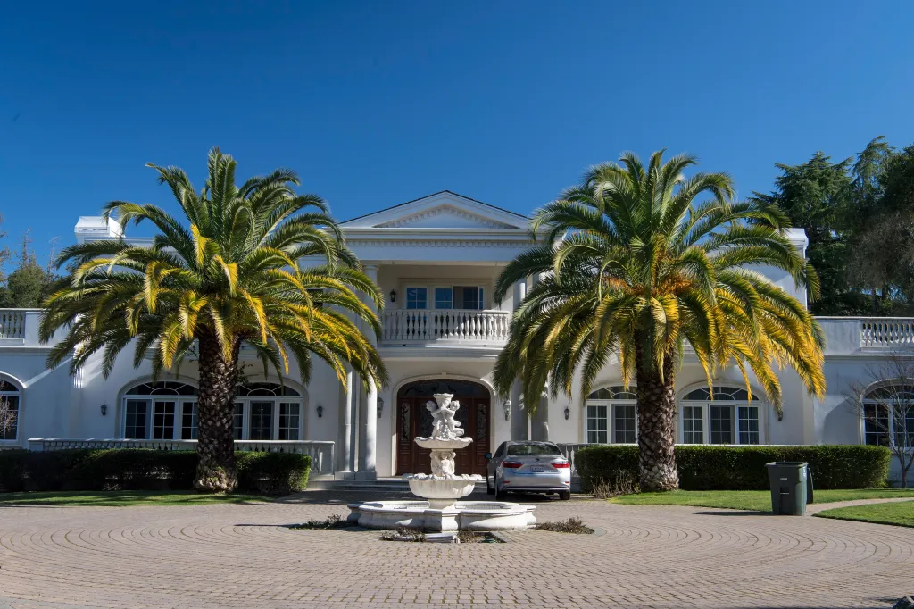 A large white house in Atherton, California, with two palm trees and a fountain in front.
