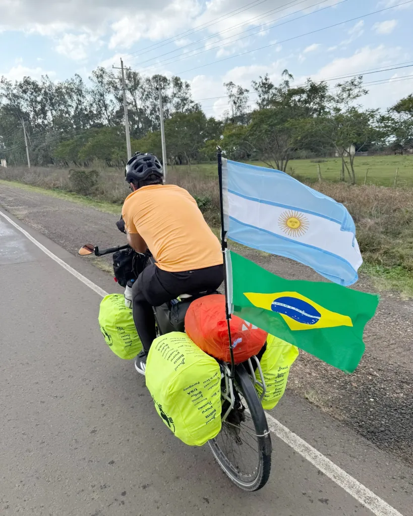 man on a bike with bright green bags hanging off the side and argentina and brazil flags. Three Argentines biked 11,000 miles through 17 countries — encountering terrorism in Colombia and altitude sickness in Bolivia — in an epic trip to watch their beloved national team defend its World Cup title.