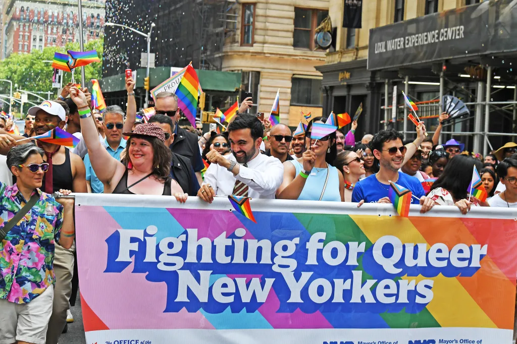 A group of people, including NYC Mayor Zohran Mamdani, carry a banner that reads "Fighting for Queer New Yorkers" at the Gay Pride Parade.