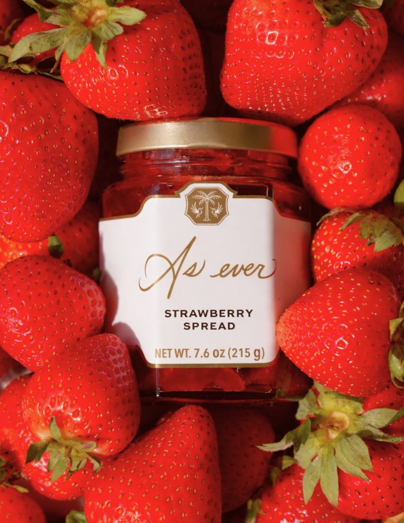 Jar of "As Ever Strawberry Spread" surrounded by fresh strawberries.