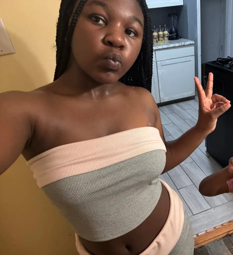 Aamina Bradley, a 14-year-old Black girl with braided hair, takes a selfie while making a peace sign.