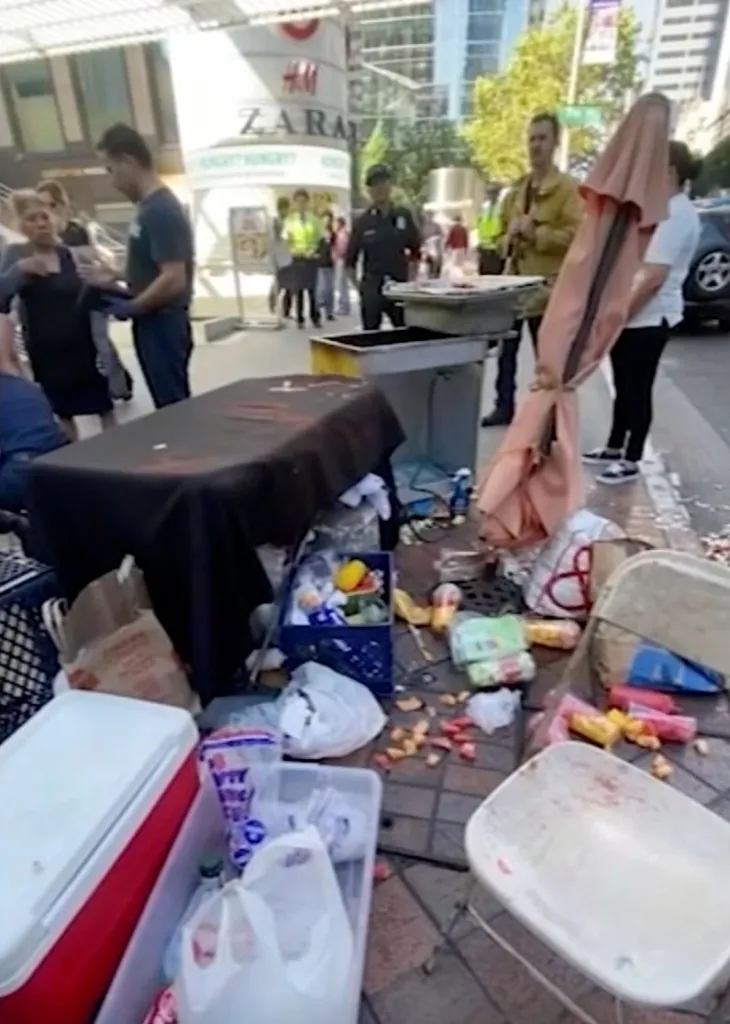 A street vending setup appears damaged, with items scattered on the ground.