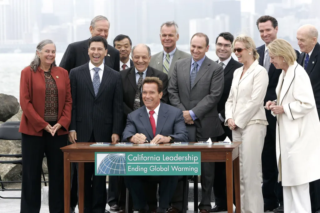 California Governor Arnold Schwarzenegger signing AB-32, the California Global Warming Solutions Act of 2006, with a group of people around him.